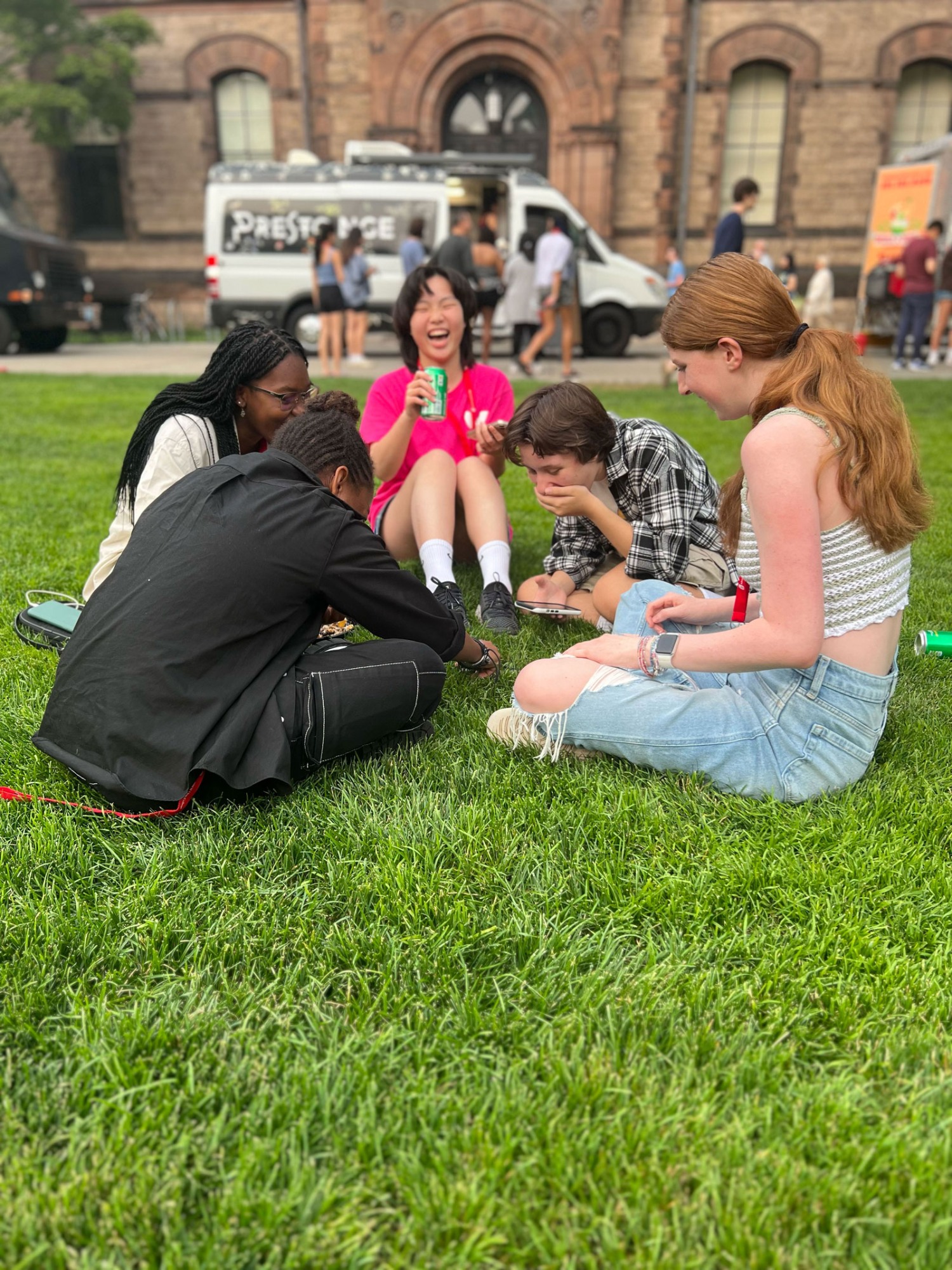 Students sit together laughing on the Main Green, with a food truck in the background