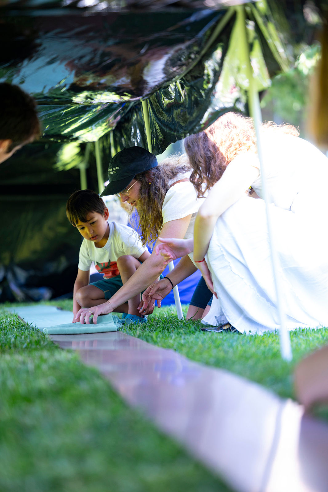 Volunteers unroll silk onto a board in preparation for the cyanotype process