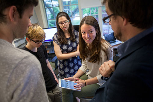 Students standing around women holding tablet