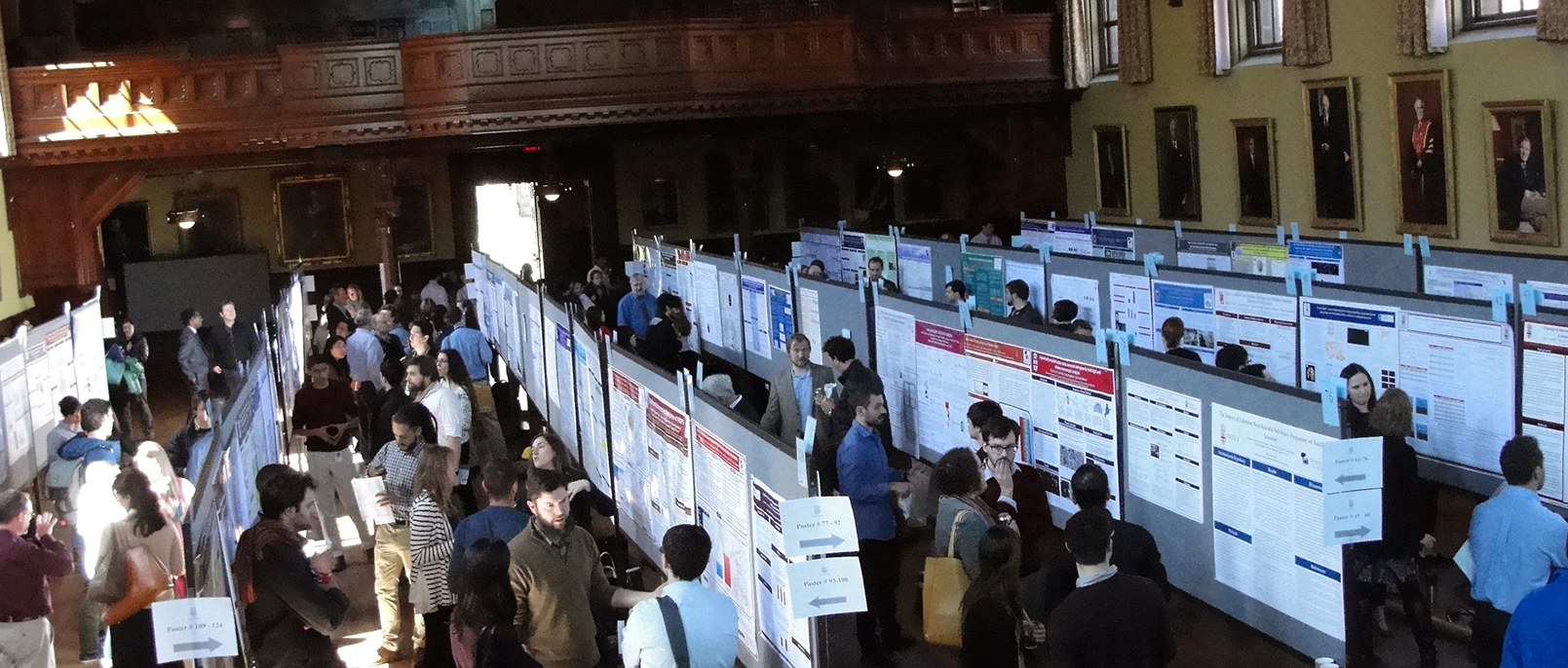 Students displaying and discussing posters in Sayles Hall