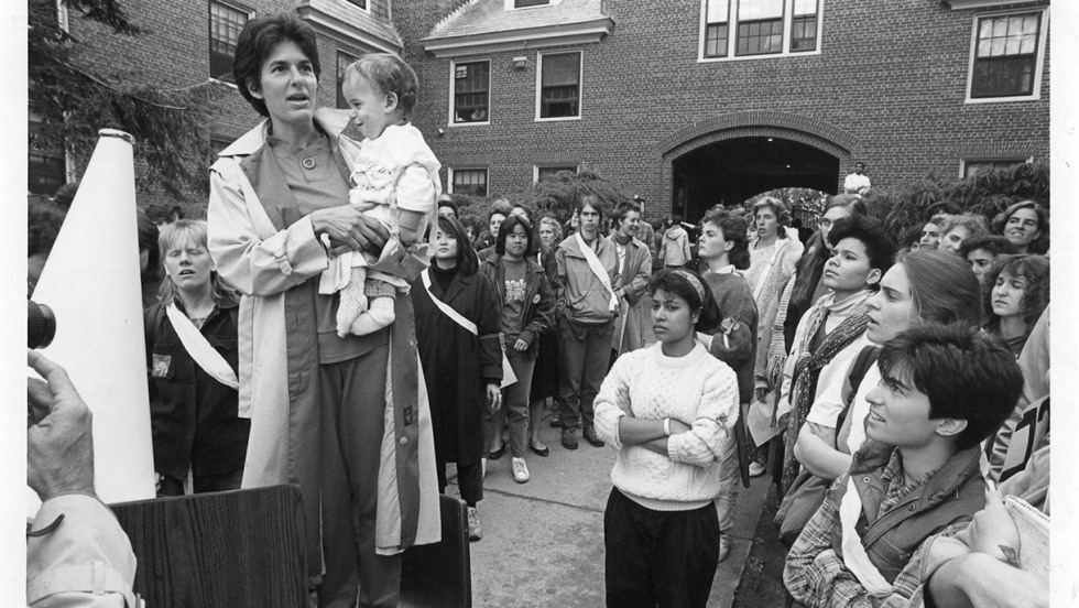 Toby Simon standing on a chair, speaking outside Brown building