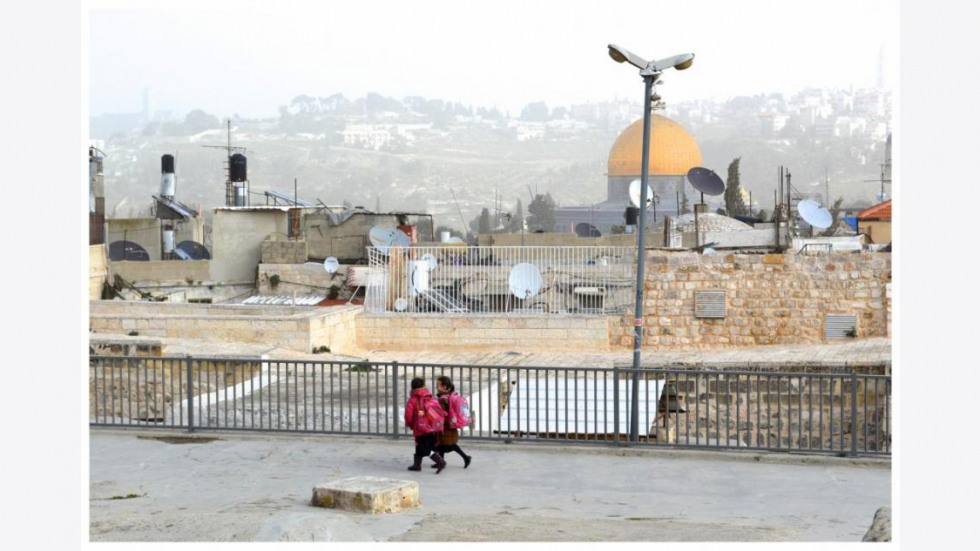 Two girls with pink backpacks walking on Jerusalem rooftops