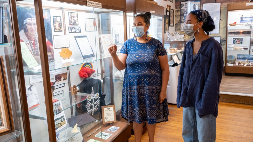 Loren Spears gesturing at a display case with Halle Bryant looking on