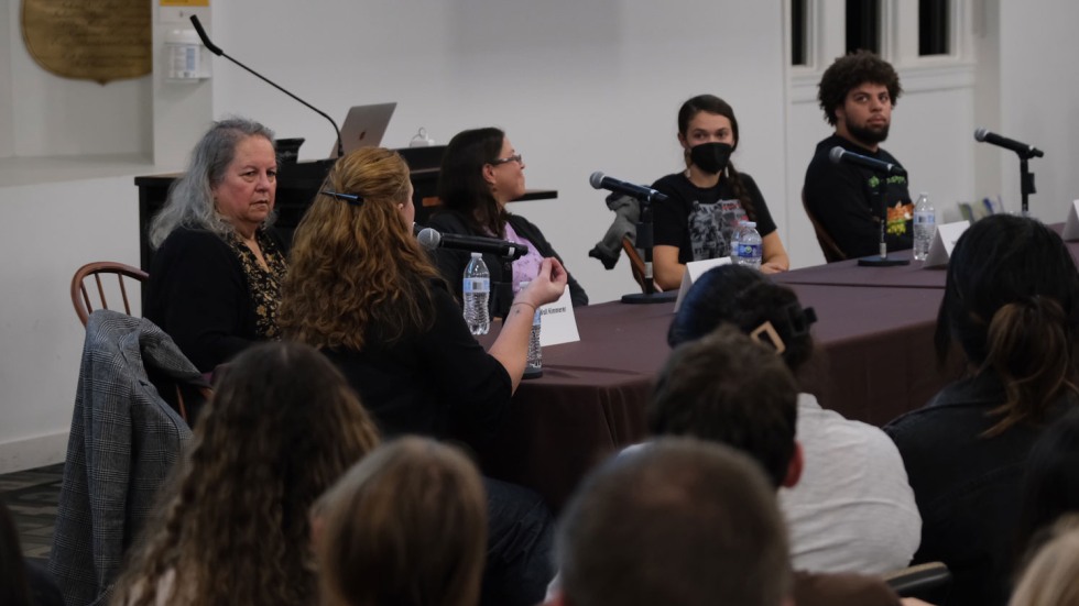 Group of people sitting at a table in front of microphones