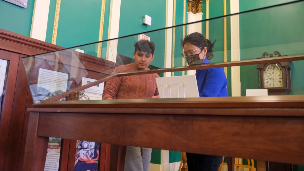 Aaron Castillo and Dana Heng talking over a display case