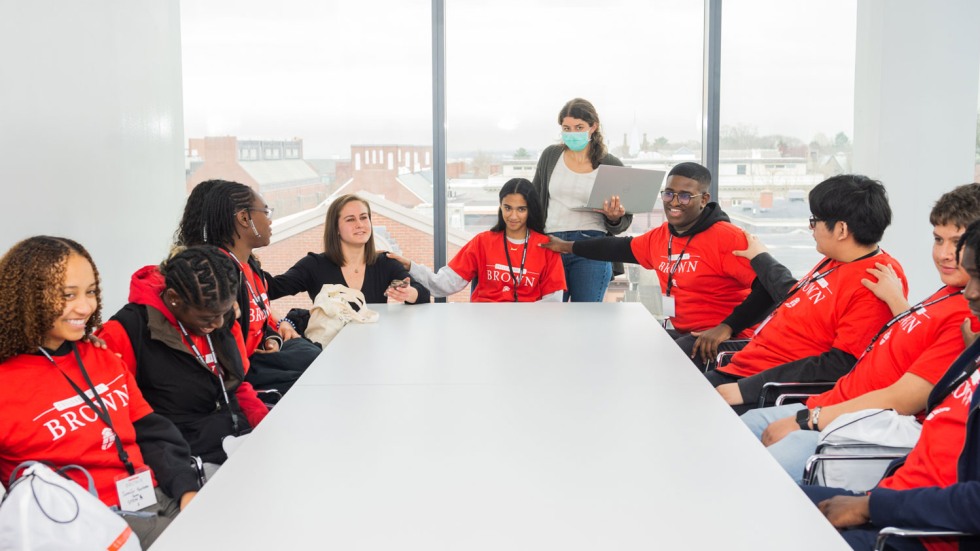 students sitting around a table and holding each other's arms