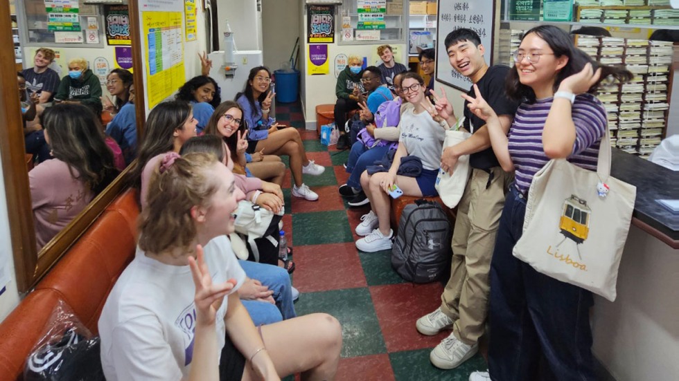 students sitting and standing in a narrow hallway 