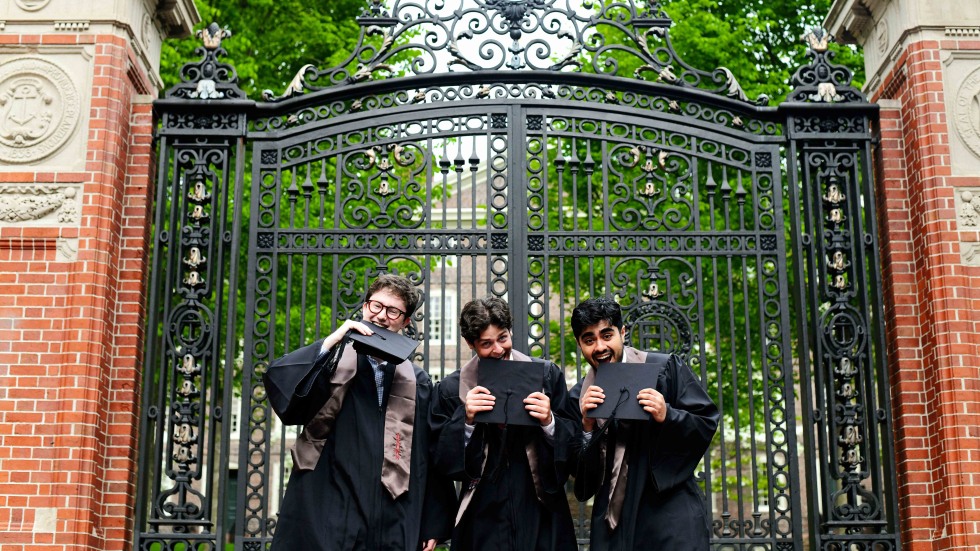 graduates standing in front of gates 