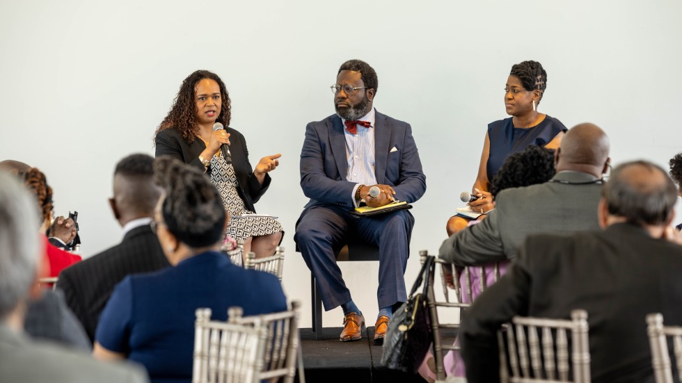 Three panelists, seated and speaking