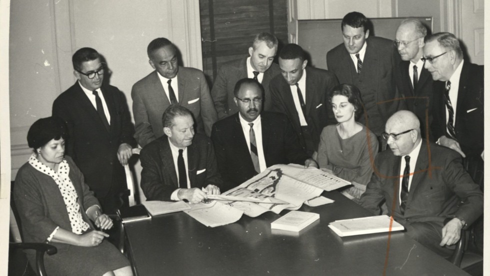 archival photo of leaders gathered behind a table