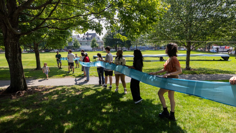 group hangs wet silk up to dry on a clothesline between ash trees