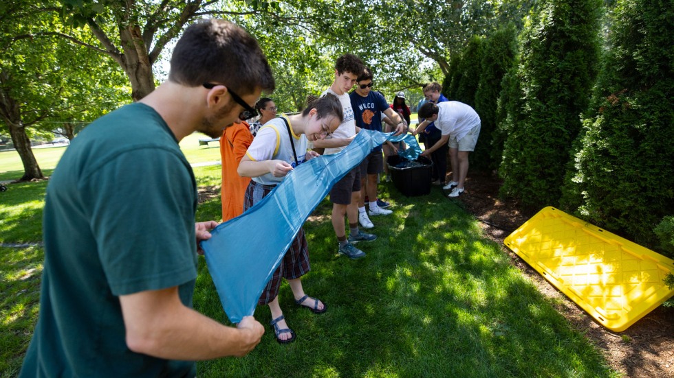 volunteers hold up silk to keep it off muddy grass