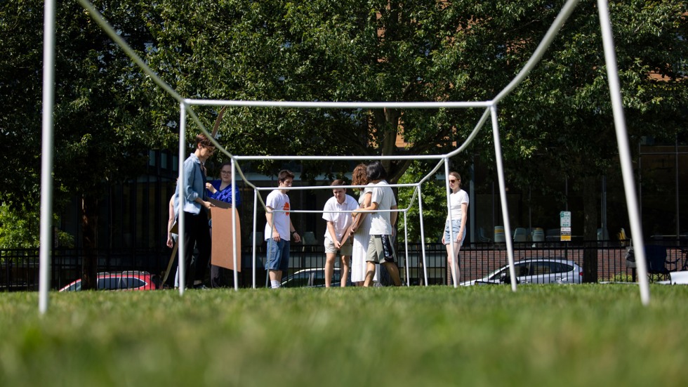 Students and volunteers set up the skeleton of a shade structure