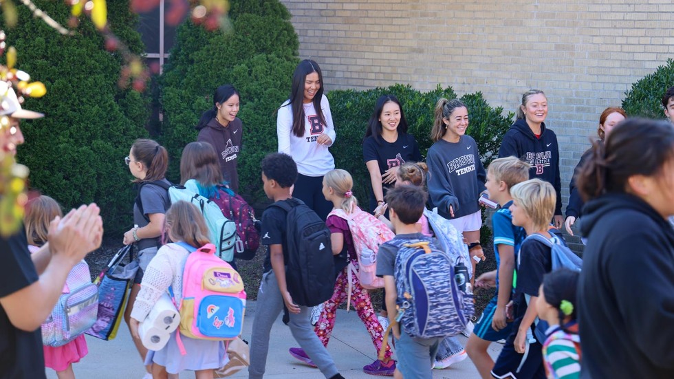 Kids walk into school surrounded by Brown student-athletes cheering them on