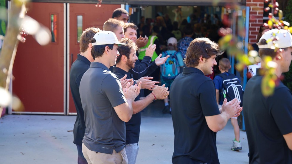 Kids walk into school surrounded by Brown student-athletes cheering them on