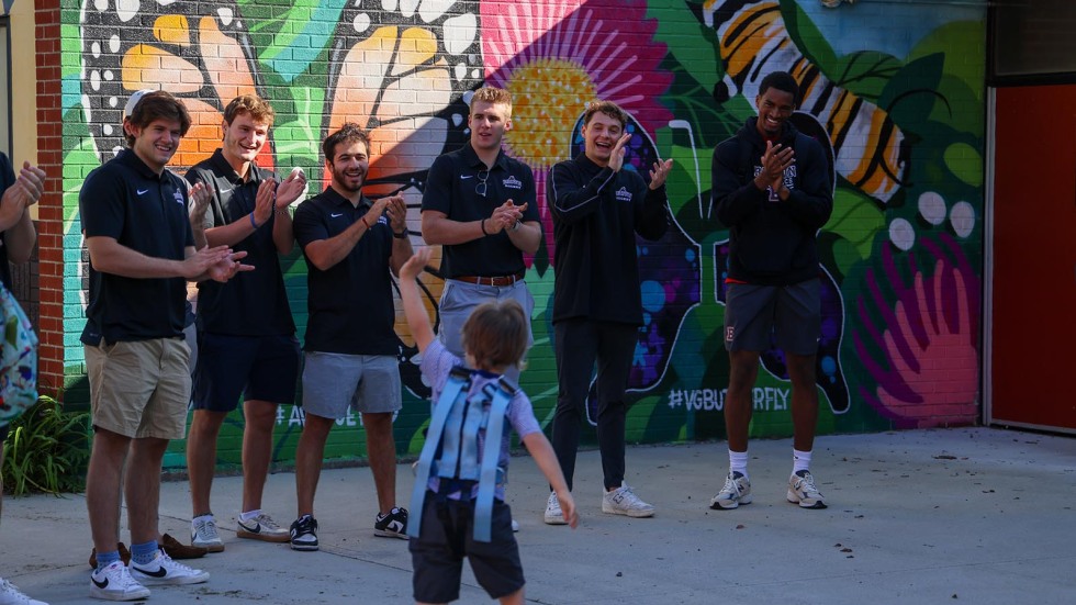 Kids walk into school surrounded by Brown student-athletes cheering them on