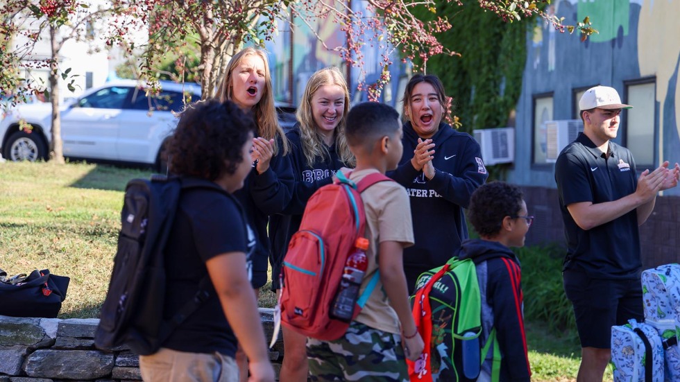 Kids walk into school surrounded by Brown student-athletes cheering them on