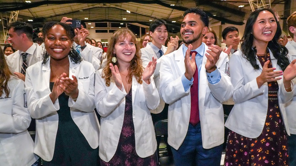 medical students wearing white coats and clapping